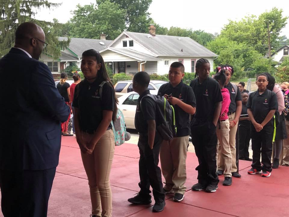 Executive Director Robert Marshall greeting line of middle school students on first day of school.
