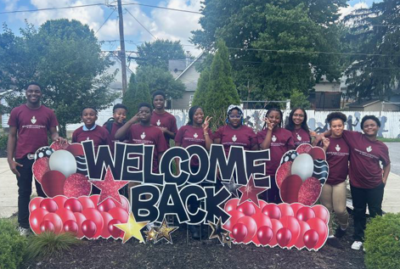 Vanguard students stand behind Welcome Back sign